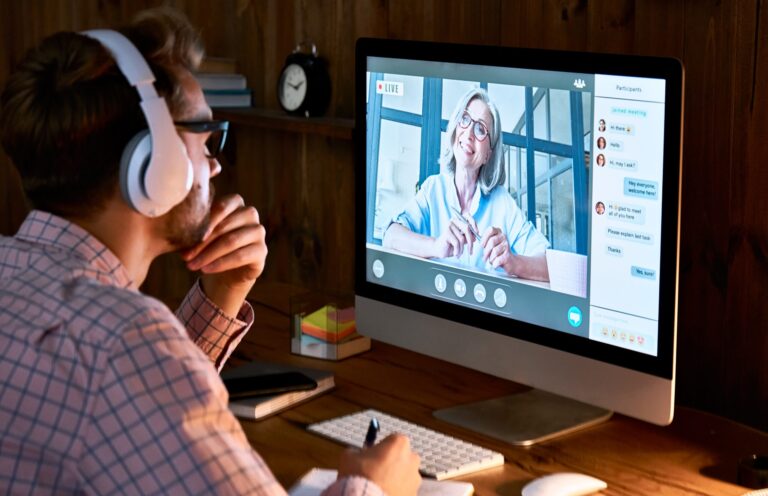 Male student wearing headphones taking online course seminar, watching webinar.